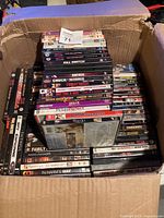 Open cardboard box filled with stacked DVD cases