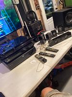 Overall view of stacked media players, speakers, remotes on table