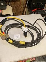 Coiled heavy-duty cord on table showing male twist-lock plug and yellow splitter