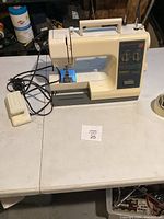 Full view of Kenmore sewing machine with foot pedal and cords on table