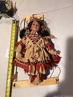Full view of porcelain doll with measuring tape