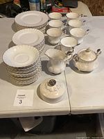 Full lot showing stacked plates, bowls, cups, creamer, sugar bowl, spare lid