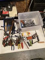 Overview of lot on table showing tote of sockets, tool pouch, hammer, pliers, screwdrivers and other tools