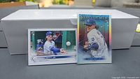 Two Bobby Witt Jr Topps rookie cards in sleeves in front of white card storage box