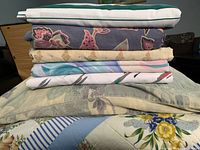 Stack of seven folded bedding pieces showing varied colors and patterns