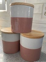 All three ceramic canisters stacked to show two-tone design and wood lids
