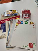 Lot overview showing decorative paper stack, Avery laser labels pack, ID card sleeve pack, bag of flag patches