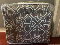 Comforter folded inside clear zip storage bag, showing brown and white geometric pattern