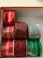 Box containing six spools of ribbon and cord in Christmas colours