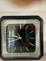 Front view showing black square frame, octagonal dial, gold markers and hands