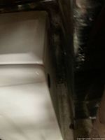 unrelated white ceramic sink partially visible beside wrapped furniture