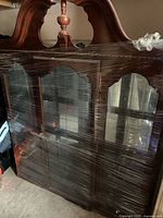 Front view of wrapped china cabinet showing glass doors and broken pediment