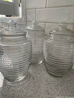Three ribbed glass jars with lids shown on countertop