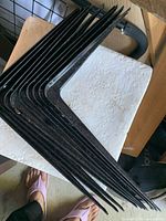 Stack of black L-shaped metal brackets showing hook ends