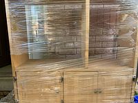 Front view of shrink-wrapped softwood hutch showing open shelves and lower cabinet