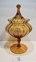 Full frontal view of amber lidded vase on pedestal