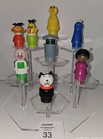 Group of nine Fisher-Price Little People figures displayed on stands