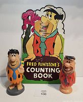 Front view of counting book and two Fred Flintstone figures