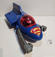 Left front view of blue Superman jet with action figure seated inside cockpit