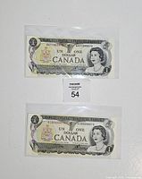 Both uncirculated Canadian $1 notes in sleeves front view