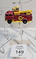 Side view of red and yellow diecast fire truck with Snoopy driver on display stand