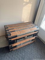 Front view of wood-slat steamer trunk with metal bands and hardware