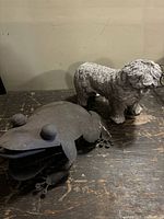 Metal frog and concrete dog on tabletop