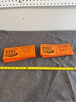 Two stacks of orange Beatles Help preview tickets with measuring tape for scale
