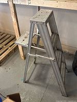 full view of aluminum three-step ladder standing folded