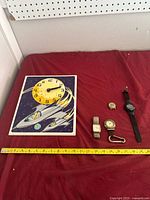All items laid out: wall clock and four watches with measuring tape for scale
