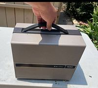 Projector closed inside its integrated case, showing handle and exterior finish