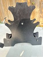 Front view of black metal barbell storage rack showing curved slot design