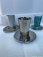 All three Kiddush cups with matching saucers displayed