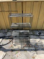 Full front view of 4-tier black metal shelf unit outdoors