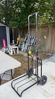 Full view of black metal hand truck standing upright on patio table area