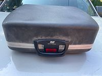 Closed hard-shell carrying case showing SCM badge and latch