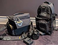 Two padded camera bags, Canon DSLR body, battery charger on floor