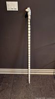 Full view of carved wooden zebra walking stick leaning against wall