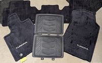 All five floor mats displayed on concrete floor: three Toyota carpet mats and two rubber mats