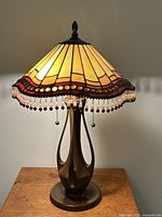 Full view of lamp on table showing base, shade, fringe