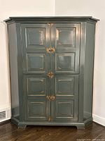 Front view of green distressed corner cabinet