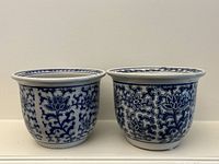 Front view of both matching blue and white ceramic jardinieres showing pattern and shape