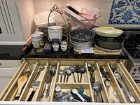 Open drawer showing flatware, serving utensils, measuring spoons and tools