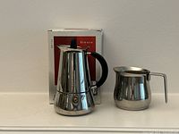 Moka pot and frothing pitcher in front of original box