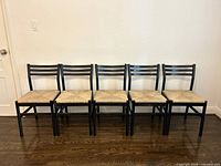 Front view of five black wood chairs with rush seats aligned