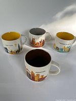 Group shot of four Starbucks You Are Here mugs