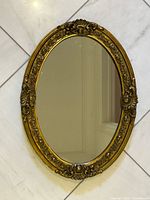 Front view of ornate gold oval mirror