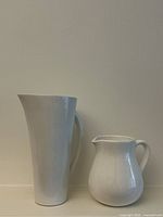 Tall and round white ceramic jugs side by side