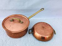 Two copper pots shown side by side on a white background.