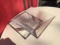 Clear square crystal bowl with Art Deco linear etchings seen from an angled top-down view, showing the bowl shape and some signatures etched inside.